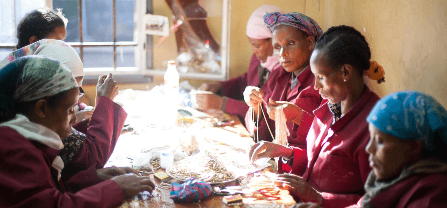 Artisans in Ethiopia sitting together at table making jewelry