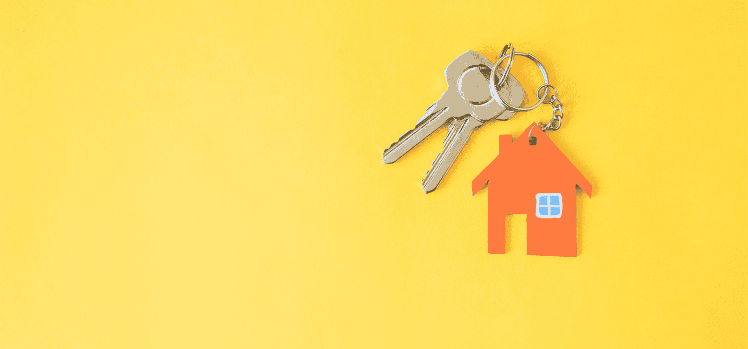 House keys with orange home-shaped keychain on yellow background