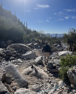 A man hiking outside around large rocks and boulders.