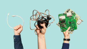 Hands holding old electronics cords and technology waste.