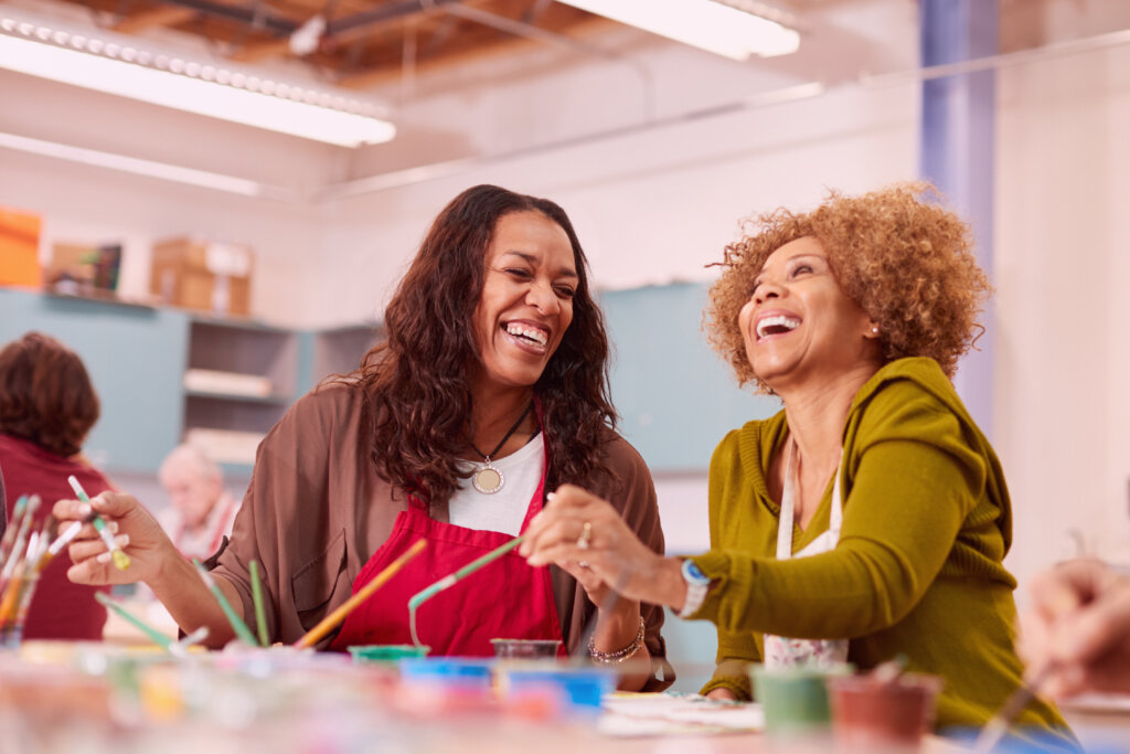 Two women enjoy a painting class in a community center.