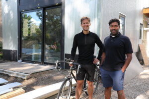 Two men standing with a bike in front of an apartment construction site.