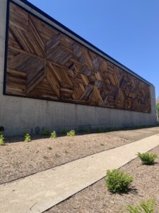 A large wooden artwork mural on the outside of a building.