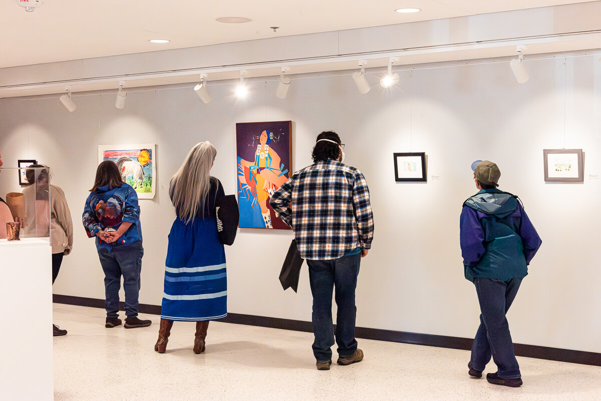 People looking at artwork on the wall inside an art gallery.