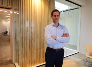 A man standing in front of a glass and wood panel.