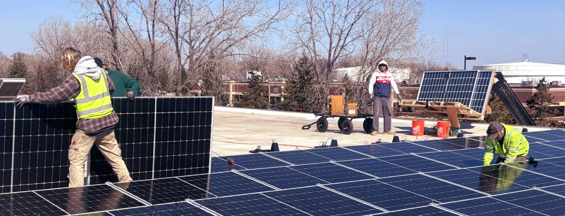 Construction workers install solar panels on the roof of a building.