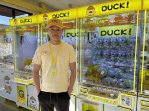 A business owner standing in front of a claw machine. 