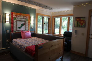 A bedroom with a quilt hanging on the wall.