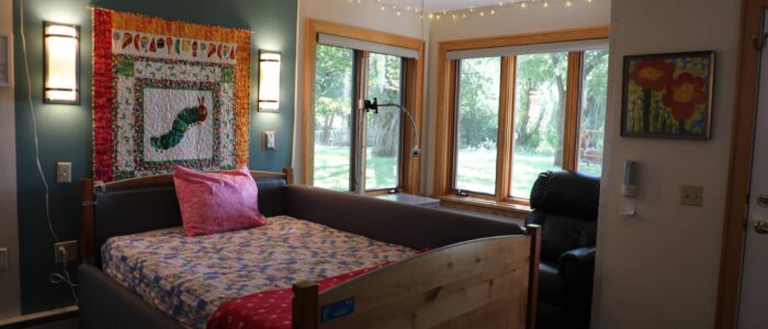 A bedroom with a quilt hanging on the wall.