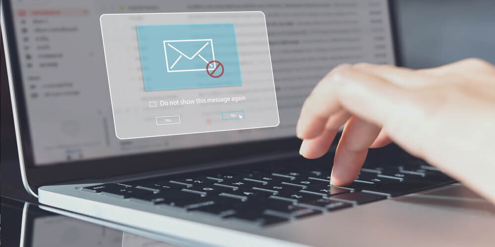 person typing on a laptop with a screen showing blocked email notification