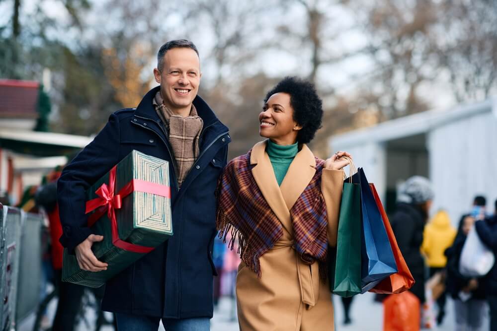 a couple holding a present and gift bags during the Holidays