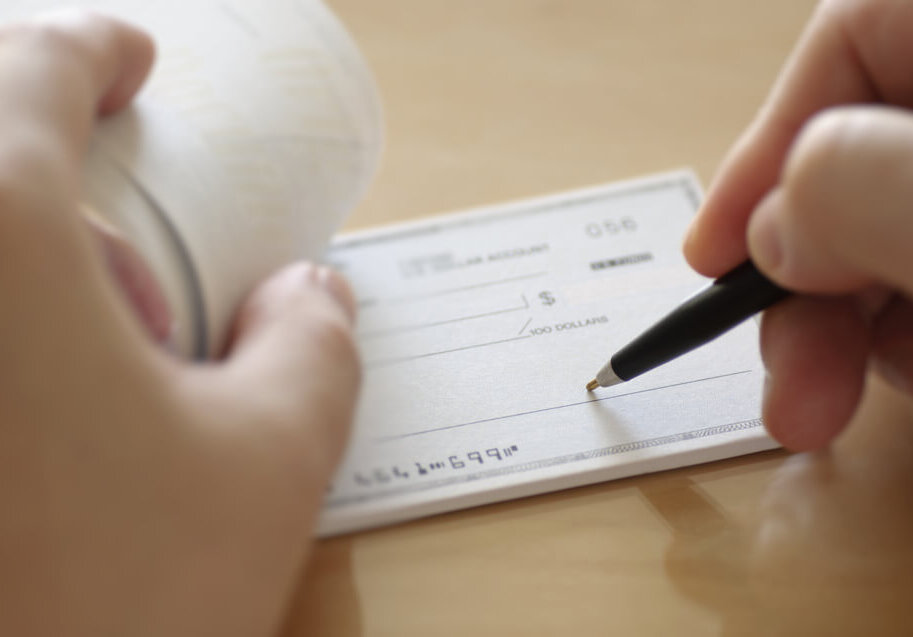 a person writing in a check book with a pen