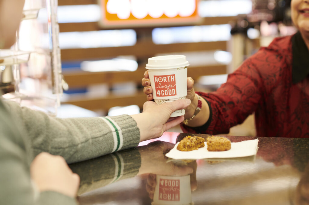 A person handing a cup of coffee to a customer.