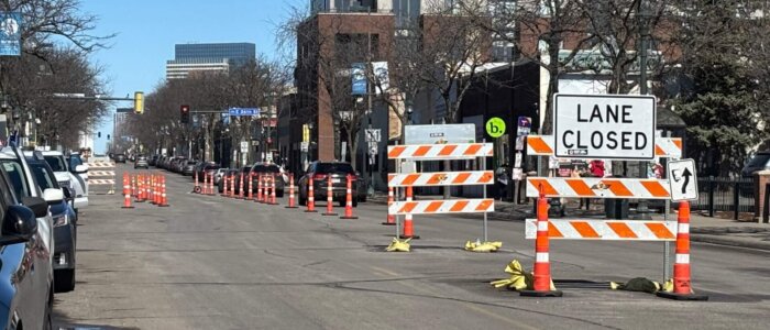 A city street with "Road Closed" signs blocking one side.