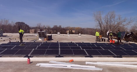 Workers installing solar panels on a flat commercial rooftop.