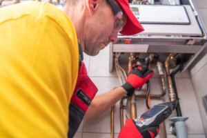 A technician doing an energy audit on a water heater.