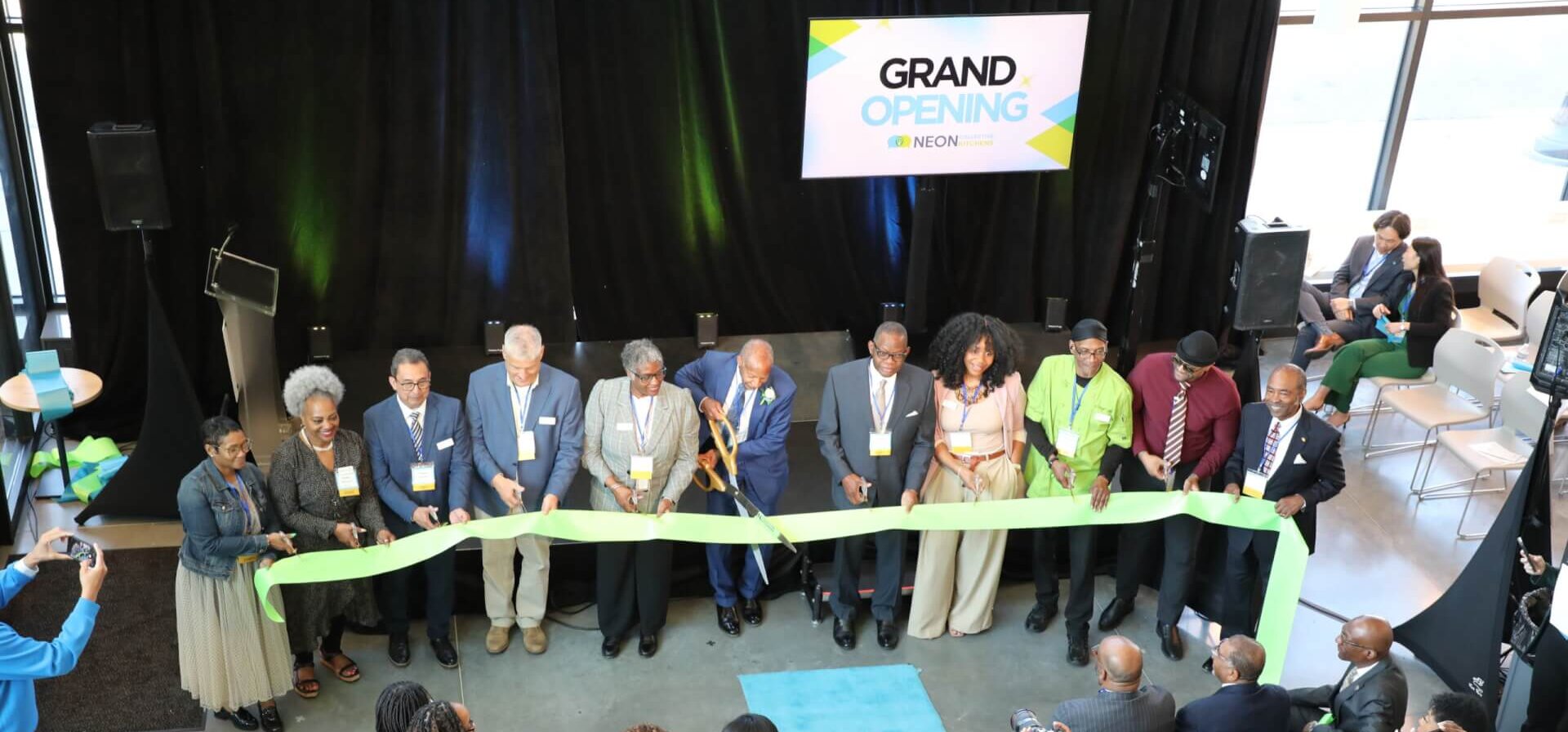 A group of NEON staff members cut the ribbon at the grand opening of NEON Collective Kitchens