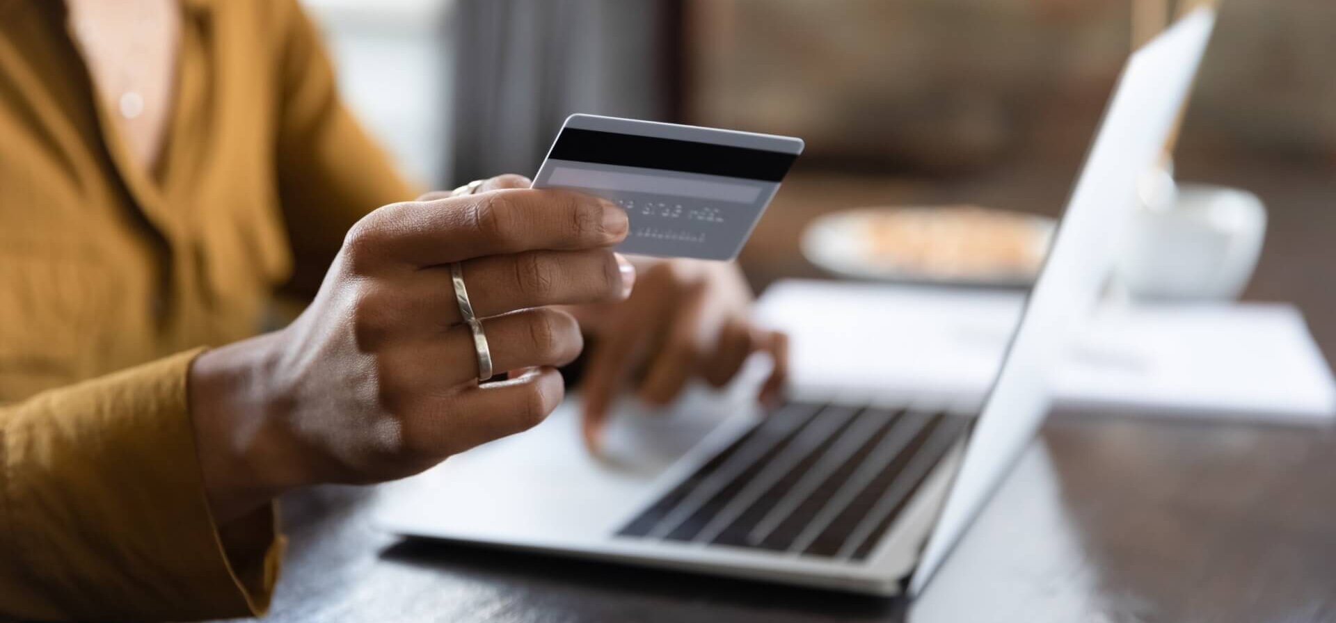A woman holding a debit card in front of a laptop computer.