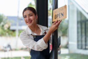 A small business owner hanging an "Open" sign on her shop.