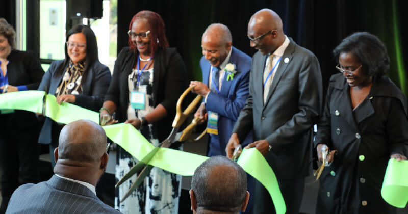 A group of community leaders cut a ribbon at a grand opening.